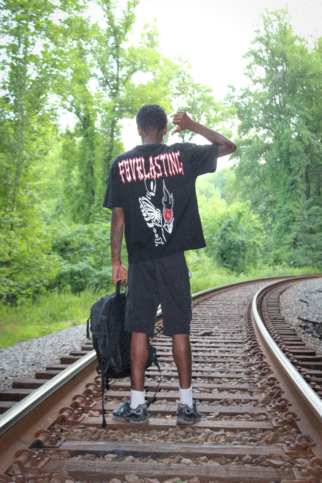 Model wearing the black FL skeleton tee on railroad tracks